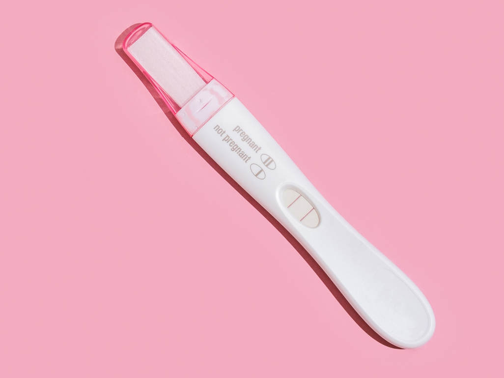 A pregnancy test on a pink background